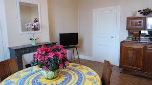 A room with a round table, a television, a cabinet, and a mirror on the wall.