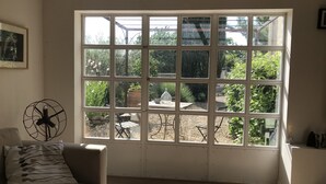 A room with a large window, a fan, and a couch. - House with calm 140m ² with swimming pool 10x5 (Campagne)