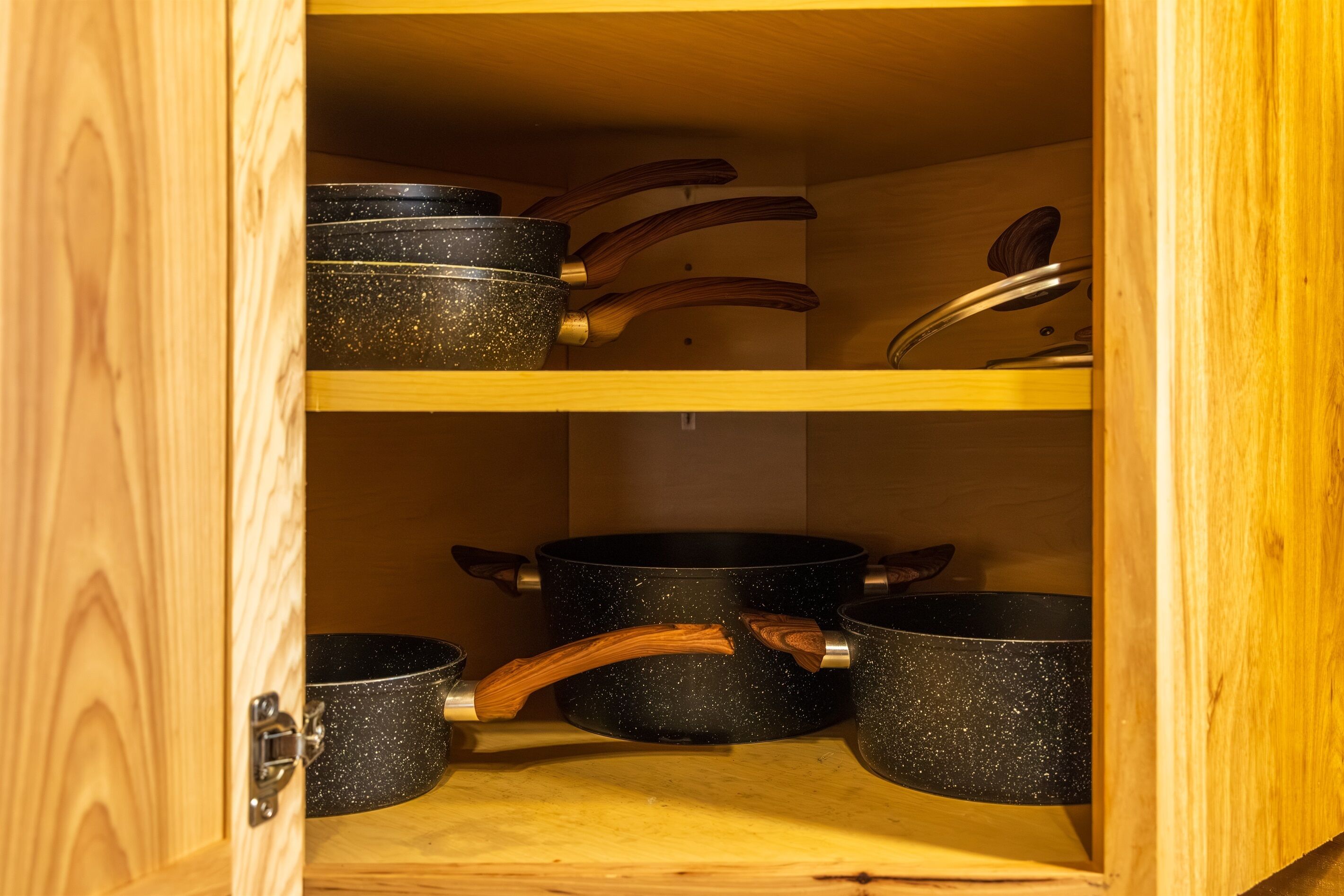 Un meuble en bois contenant plusieurs pots noirs à motifs et doté de poignées en bois.