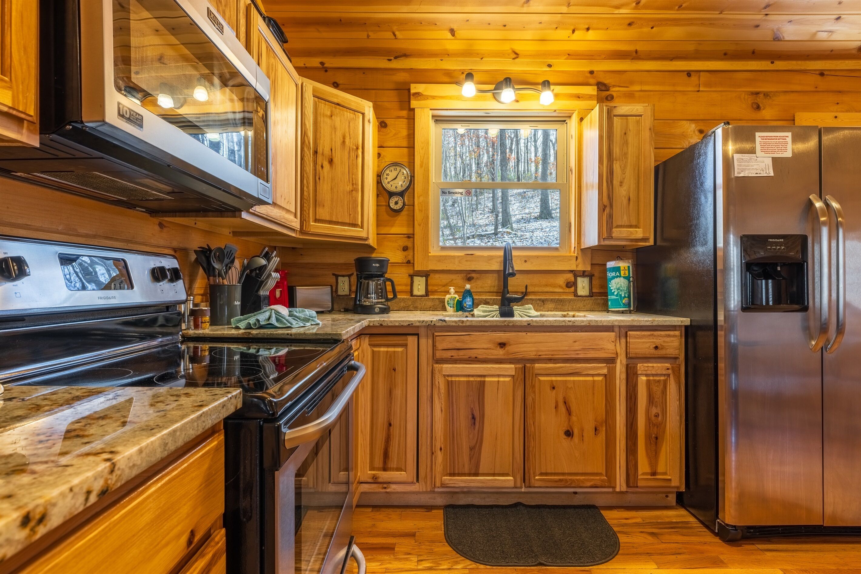 Une cuisine rustique, située dans une cabane en bois, équipée d’un réfrigérateur en acier inoxydable, d’une cuisinière et de meubles de rangement en bois.