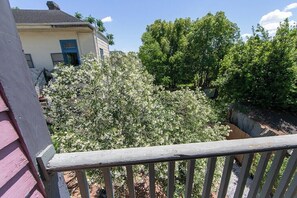Un balcone con vista su una casa e degli alberi.