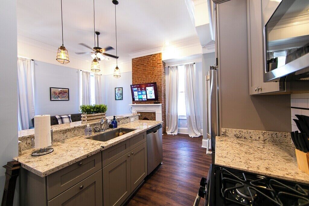 A modern kitchen with granite countertops, stainless steel appliances, and pendant lighting.