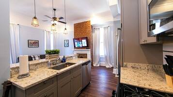 A modern kitchen with granite countertops, stainless steel appliances, and pendant lighting.