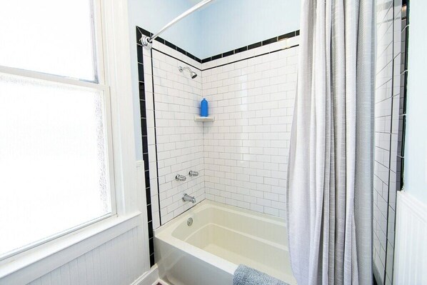 A bathroom with a bathtub, a shower, and a window.