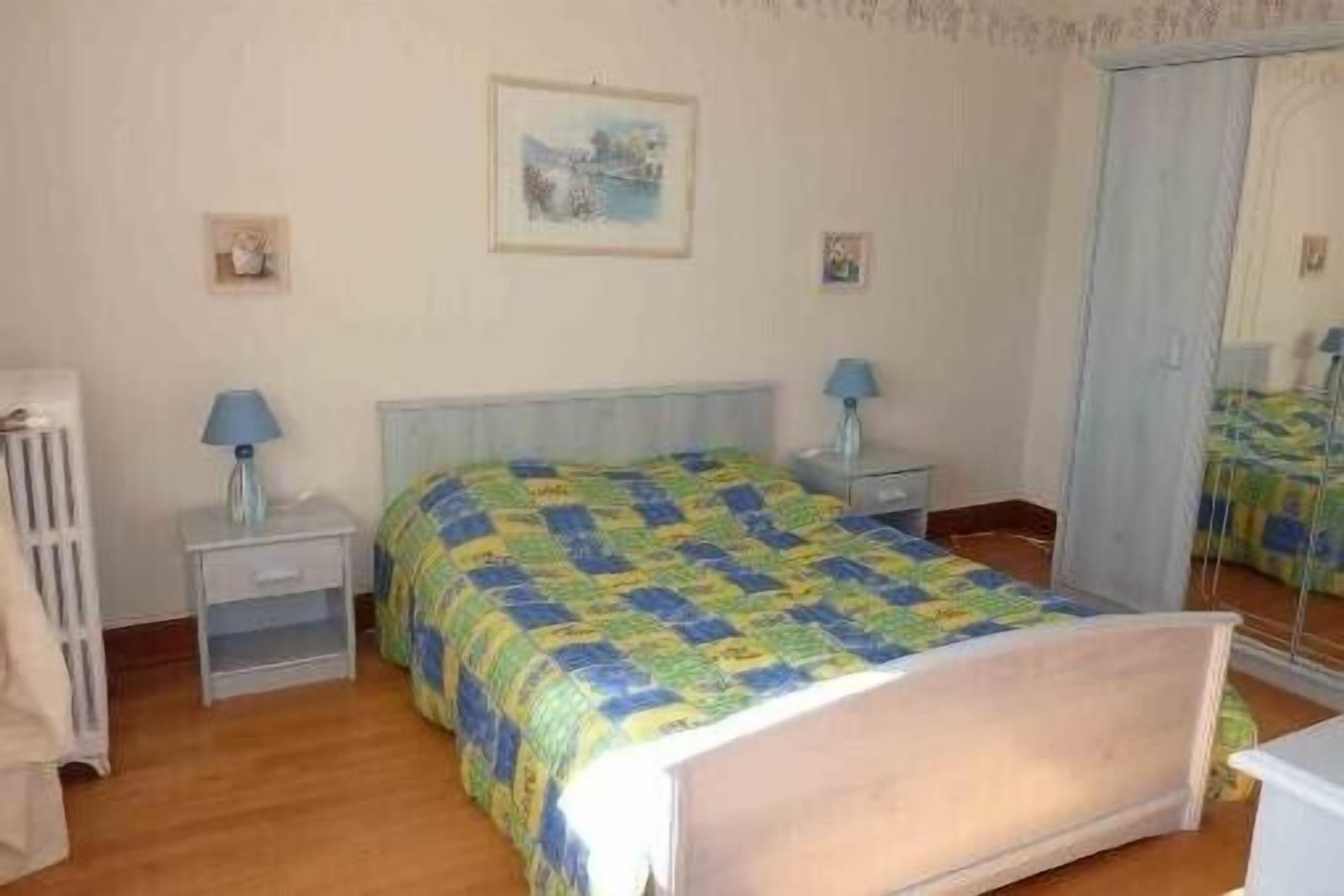 Une chambre à coucher avec un lit, des tables de chevet, un miroir et une armoire.