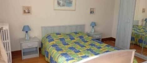 Un dormitorio con cama, mesitas de noche, un espejo y un armario.