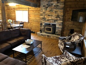Cozy living room with a stone fireplace, leather sofa, and wooden coffee table.