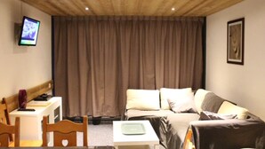 Una habitación con cama, escritorio, silla, televisor y cortina.