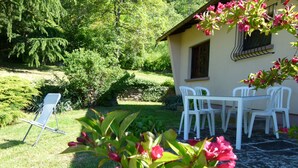 Un jardín con una mesa y sillas, césped y un edificio con una ventana.