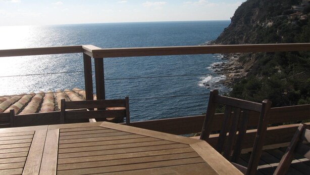 A wooden deck with a table and chairs overlooking a coastal view. - In front... only the sea (Carqueiranne)