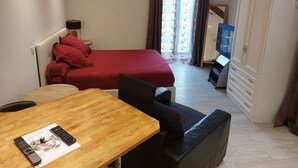 Una habitación de hotel con cama, escritorio, silla, televisión y armario.