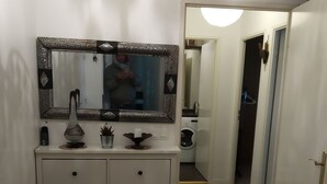 A hallway with a white dresser, a decorative mirror, a chandelier, and a red carpet. - Entire home cozy and ideally located (Saint-Denis)