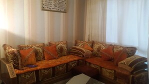 A corner sofa with patterned cushions and a decorative wall hanging. - Entire home cozy and ideally located (Saint-Denis)