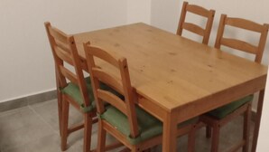 A wooden dining table with four chairs, each with a green cushion. - Entire home cozy and ideally located (Saint-Denis)