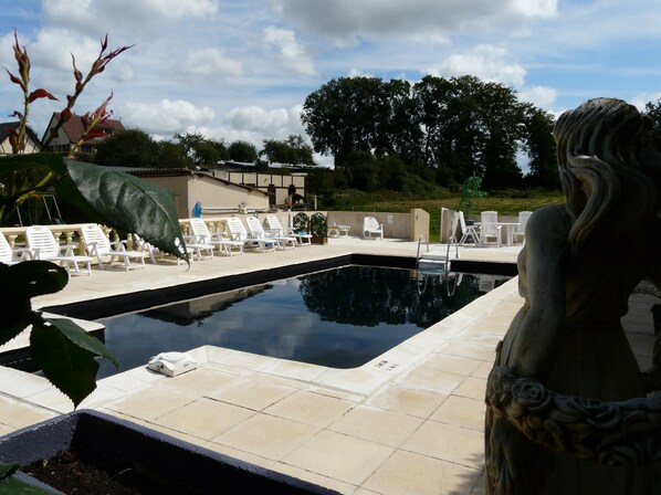 A swimming pool with lounge chairs and a statue.