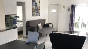 Uma sala de estar moderna com área de jantar, um sofá e uma cozinha.