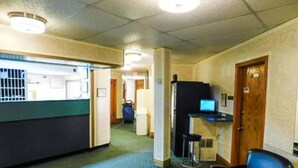 A hotel corridor with a reception desk, a computer desk, and a seating area. - Filmores Hotel (Toronto)