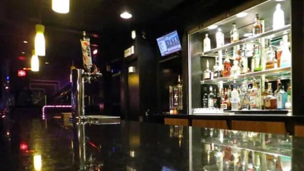 A bar area with a polished floor and shelves of bottles. - Filmores Hotel (Toronto)