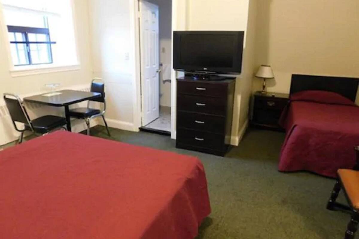 A hotel room with two beds, a desk, a chair, a television, and a nightstand.