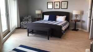 A bedroom with a bed, bench, two nightstands, a lamp, and a chair. - Boardwalk Beauty! Two-Story Oceanview Condo (Rehoboth Beach)