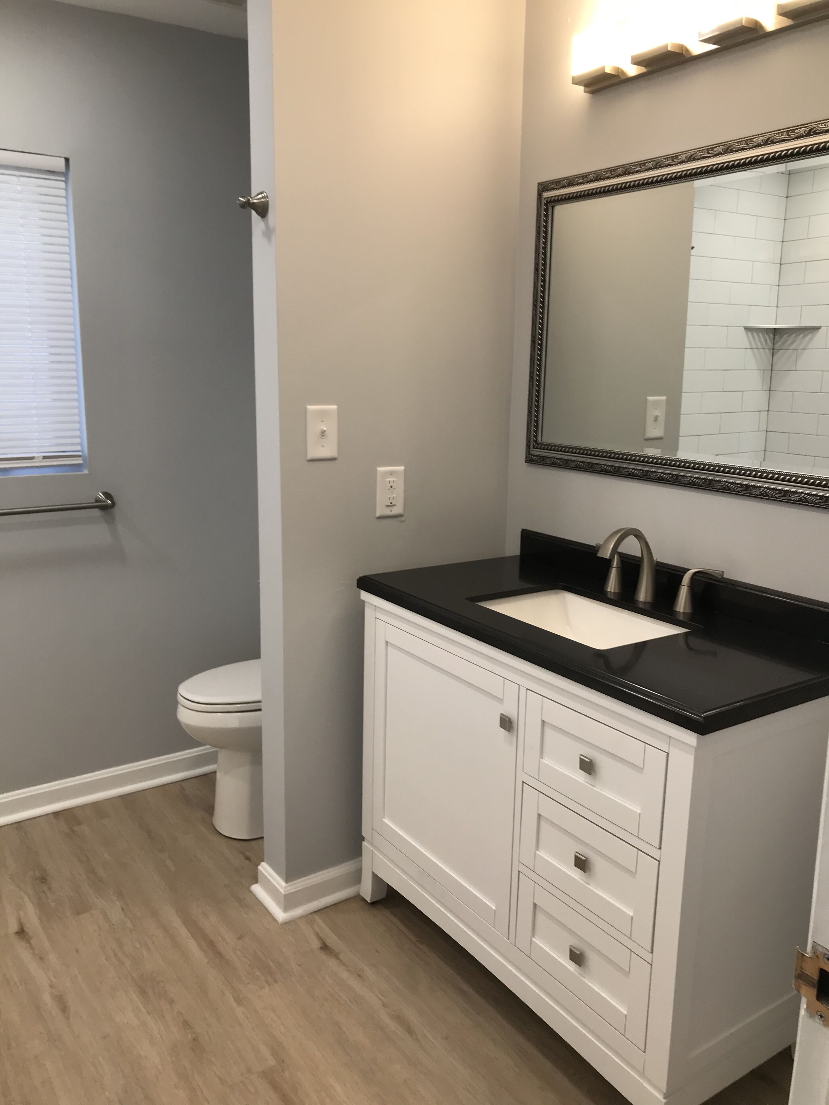 A bathroom with a white toilet, a black countertop sink, and a white vanity with drawers.