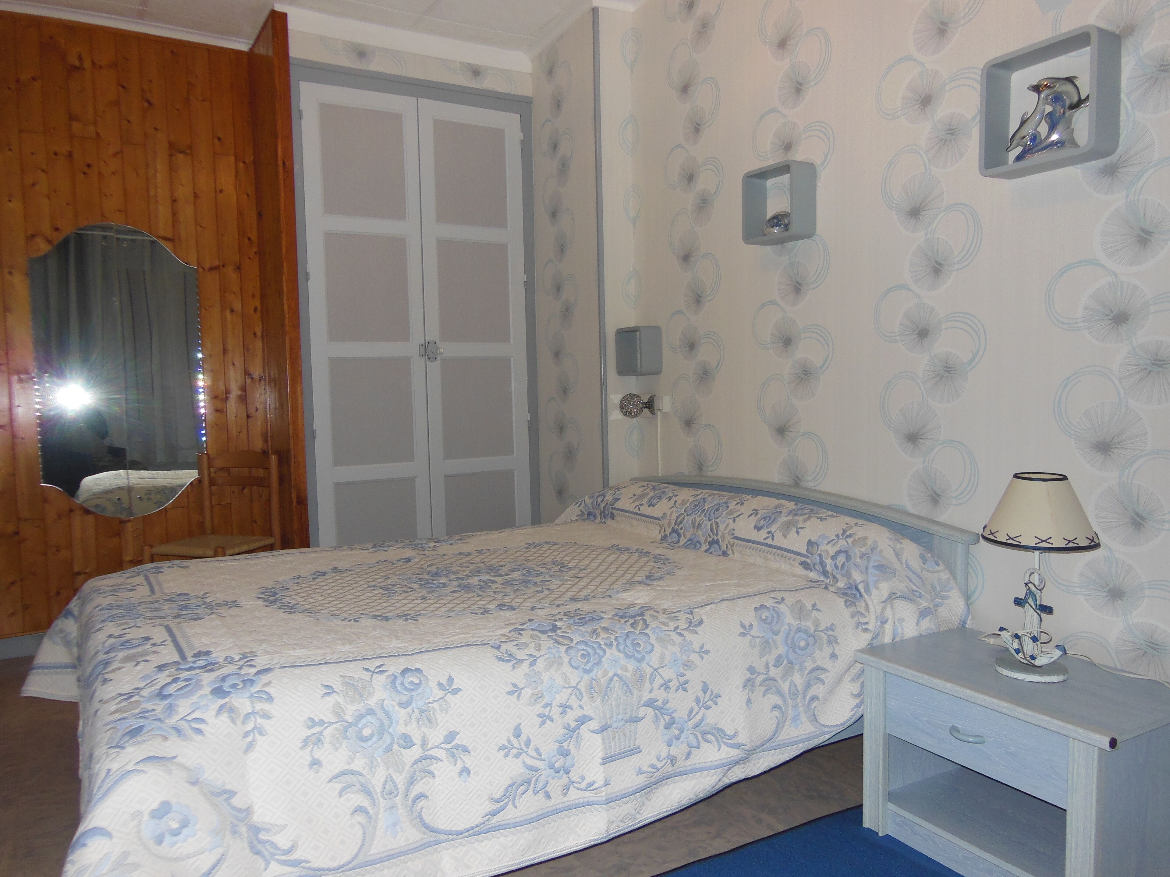 A bedroom with a bed, a nightstand, a mirror, and a wardrobe.