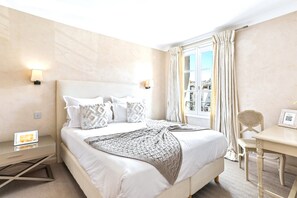 Ein Hotelzimmer mit einem großen Bett, Nachttischlampen, einem Schreibtisch und einem Sessel.