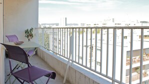 A balcony with a table and chairs, a potted plant, and a view of a cityscape with buildings. - Charm, quietness, beach, city, ideal location and 5 minutes from motorways (Marseille)