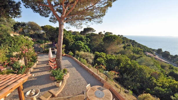 A patio area with a round wooden table and chairs, surrounded by a gravel path and a wooden fence. - T4 - 95 m2, Porticcio, garden, garage option, large bedding 180+160. Wifi Fiber (Grosseto-Prugna)