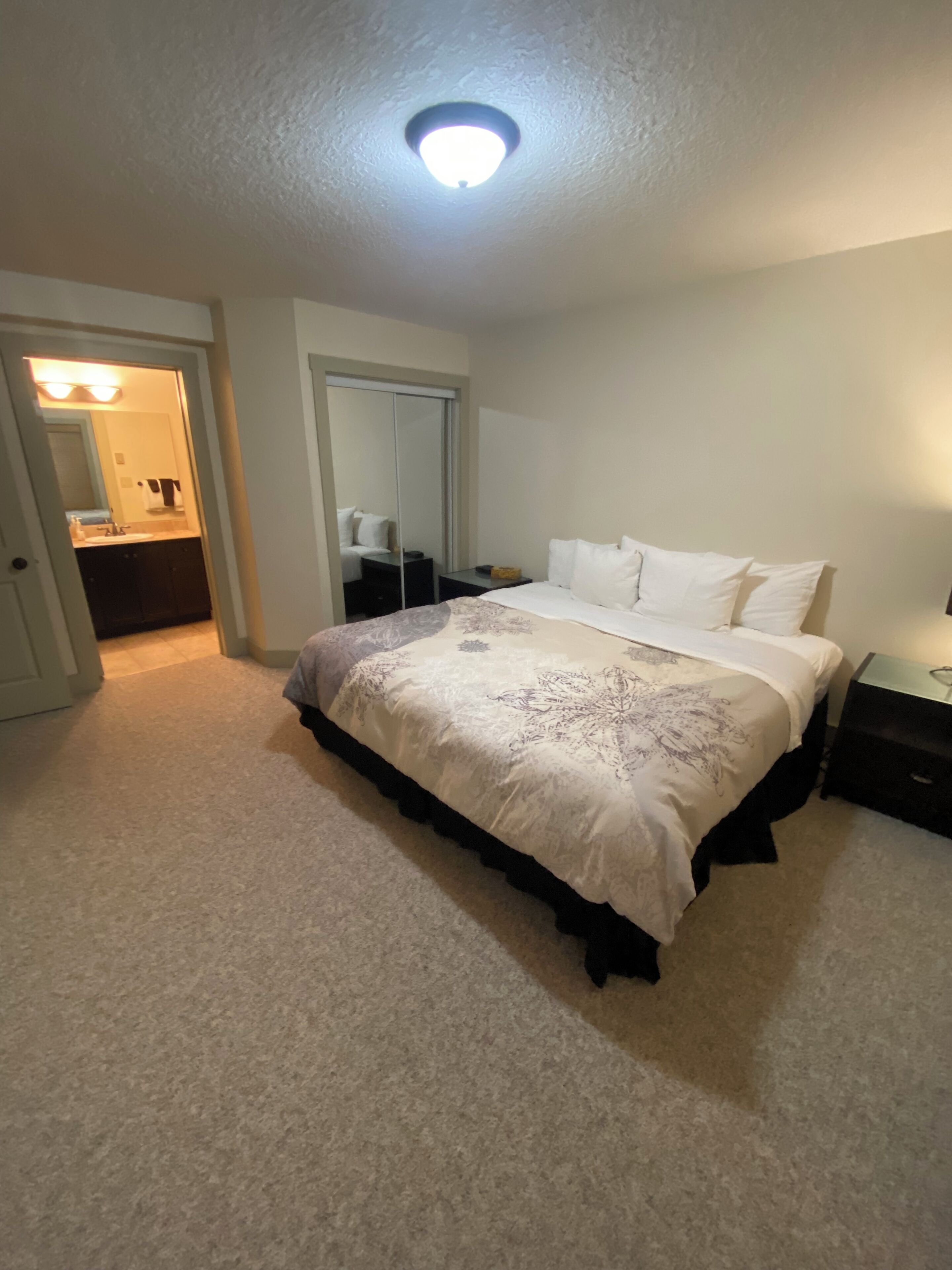 Een slaapkamer met een bed, nachtkastje, dressoir en inloopkast.