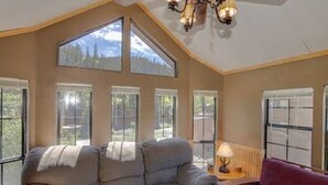 A cozy room with a large window, a sofa, and a lamp. - Cozy Cabin on the River. 1 Bed 1 Bath Patio w/  BBQ (Breckenridge)