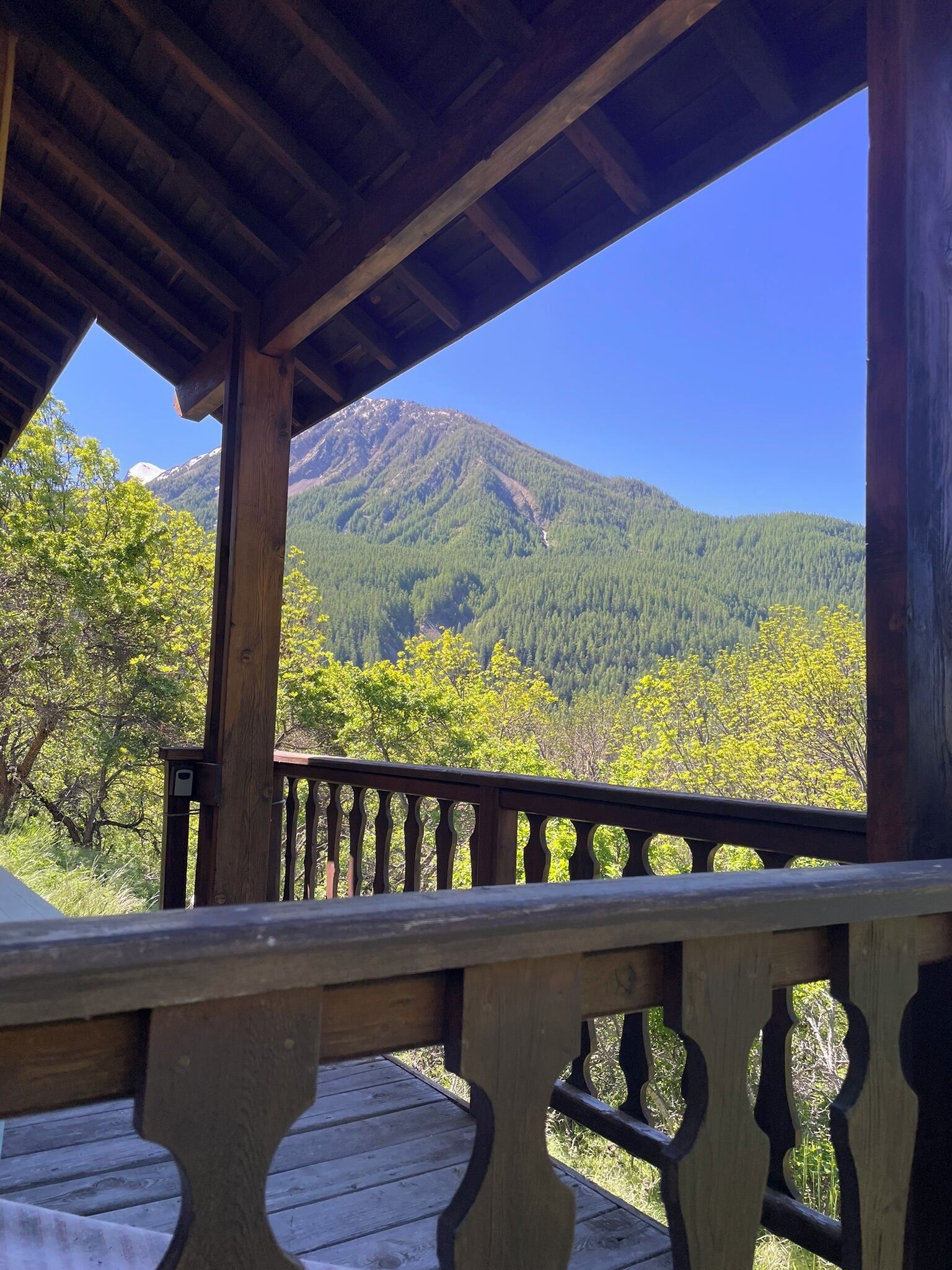 A wooden deck with a railing overlooking a forested mountain.