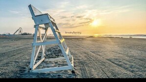 A lifeguard stand on a beach with a sunset in the background.