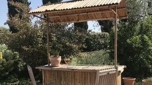 An outdoor bar area with a wooden pergola, two folding chairs, and a small table. - Charming villa with private pool (Arles)