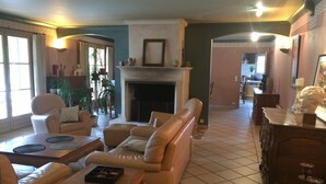 A spacious living room with a fireplace, leather sofas, a coffee table, and a dining area with a wooden table and chairs. - Charming villa with private pool (Arles)