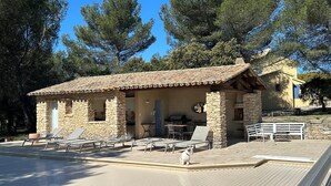 A stone building with a tiled roof, outdoor seating, and a small pool area.