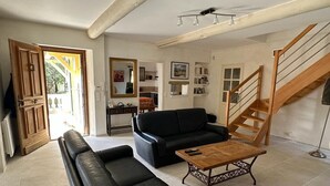 A living room with a black leather sofa, a wooden coffee table, and a staircase.