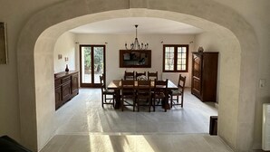 A spacious dining area with a high arched ceiling, a chandelier, and a view through large windows.