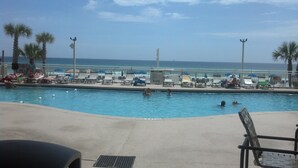 A pool area with lounge chairs and umbrellas, a sign prohibiting diving, and a view of the ocean.
