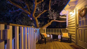 A wooden deck with two chairs and a table, surrounded by a white picket fence. - Gulf Front Guest House (Anna Maria)