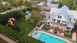 A large house with a swimming pool, a fenced yard, and a colorful play structure. - Gulf Front Guest House (Anna Maria)