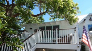 A two-story house with a balcony and an American flag. - Gulf Front Guest House (Anna Maria)