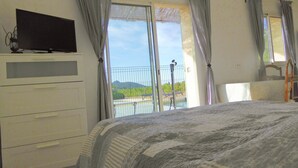 A bedroom with a bed, a television on a dresser, and a balcony with a view of greenery and a fence. - Pleasant, sunny villa (Vaison la Romaine)