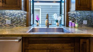 Una cocina de diseño moderno, con un lavamanos de acero inoxidable, armarios de madera y salpicadero con mosaicos.