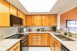 Une cuisine avec des meubles en bois, un four à micro-ondes, une cuisinière, un évier et une lucarne.