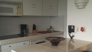 Een moderne keuken met witte kasten, een magnetron, een koffiezetapparaat en een groot keukenblok met een kom.