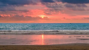 Una playa con un atardecer sobre el océano.