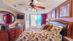 A hotel room with a bed, a ceiling fan, a dresser, a TV, and a view of the ocean. - Experience South Shore Villas Unit 503's beauty - a Premium Oceanfront condo with a pool, lazy river, and grills for lasting memories. (North Myrtle Beach)