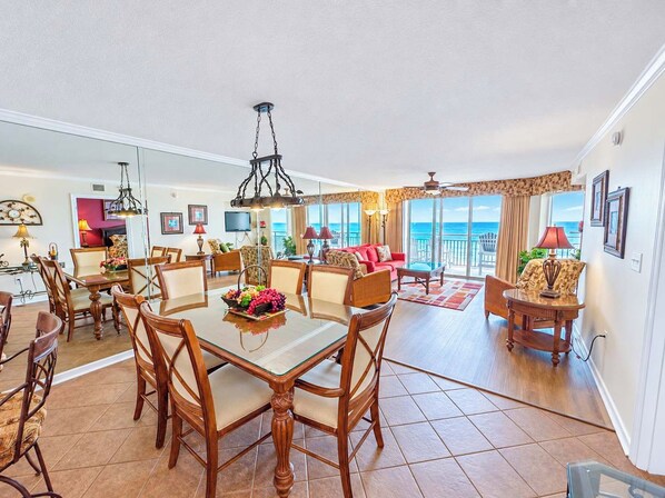 A spacious living area with a dining table, chairs, and a view of the ocean.