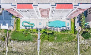 Ein Luftbild eines Hotels mit großem Schwimmbad, Kinderspielbereich und angelegtem Garten.
